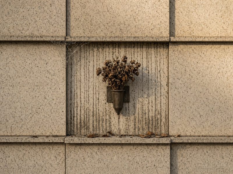 Illustrative example, before: a columbarium niche front with drip stains, a cobweb, dead flowers, and leaves on the ledge